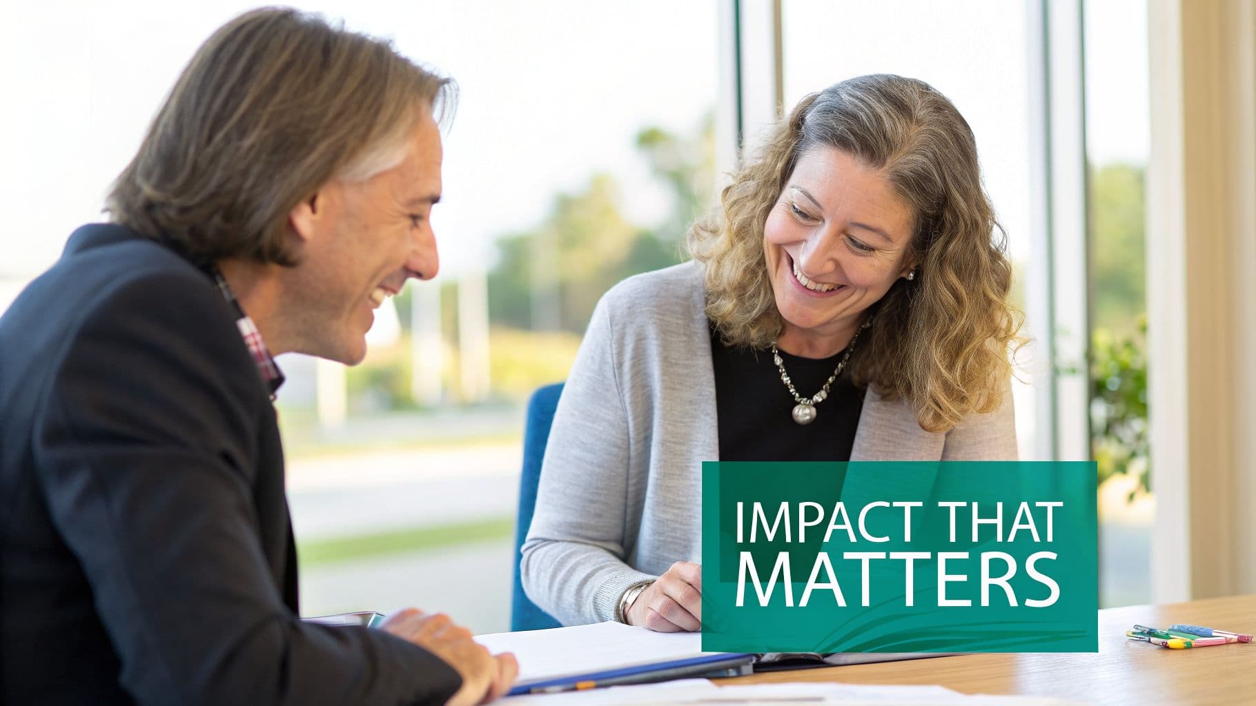 Two professionals smiling and reviewing documents together