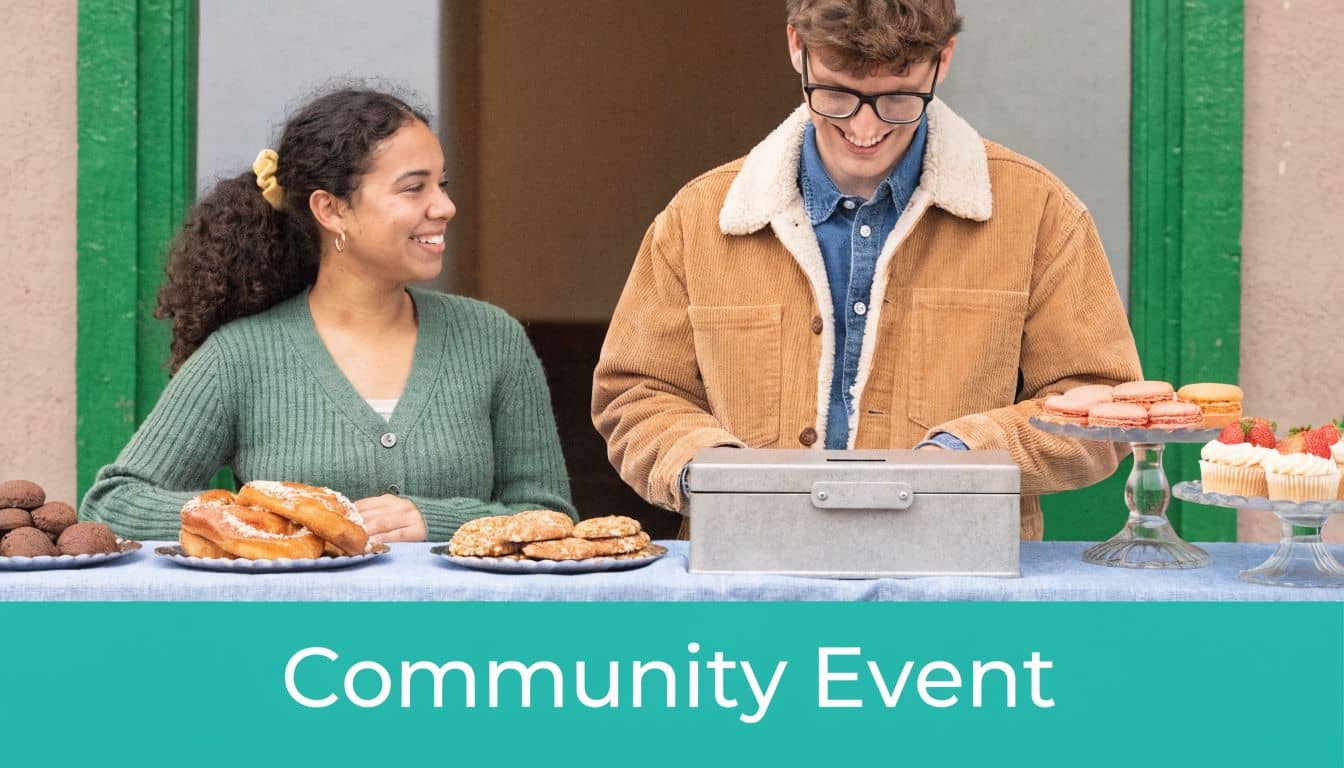 Young woman and man smiling while running a bake sale table at a community event.