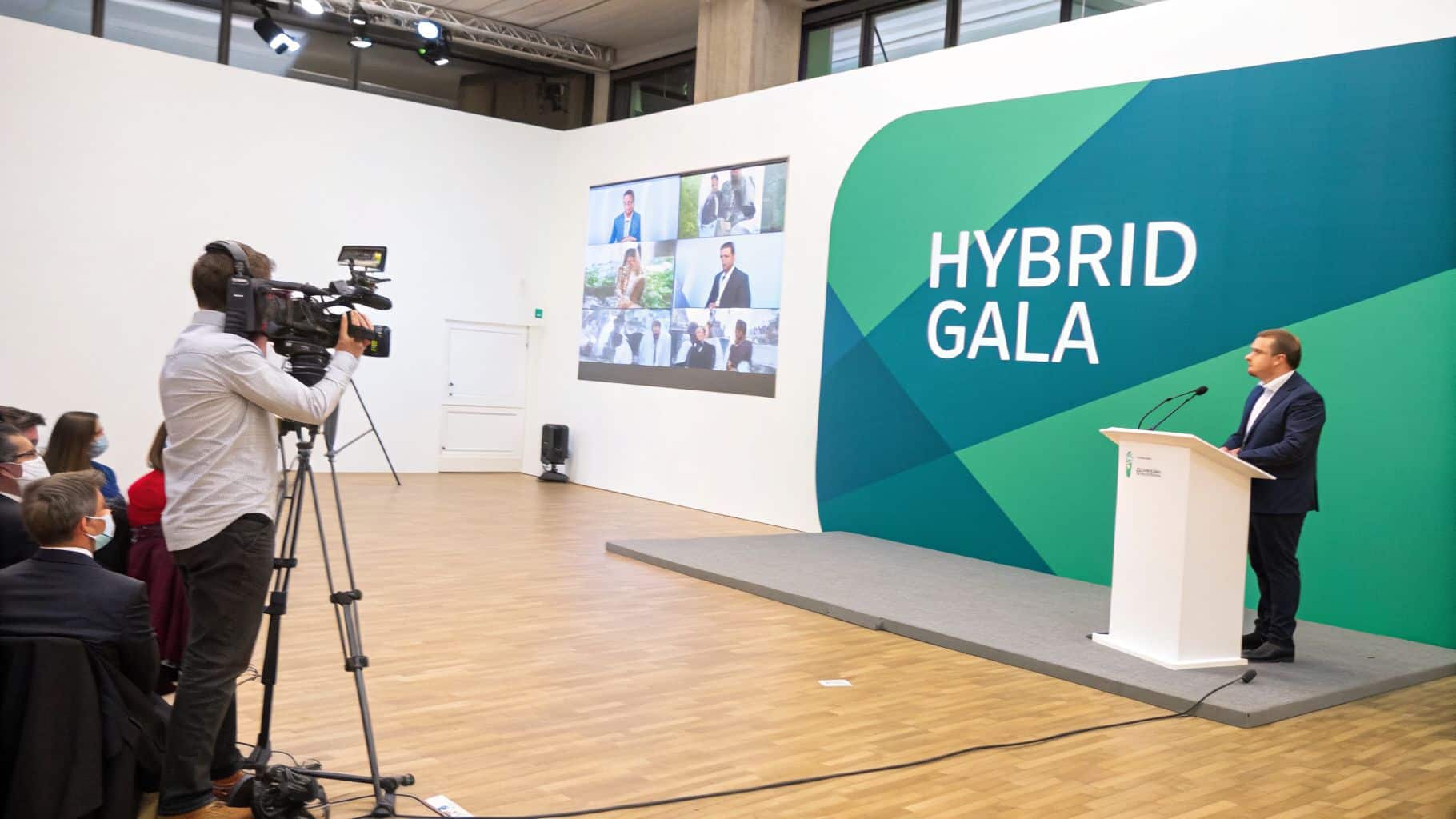 Cameraman films a speaker at a podium during a Hybrid Gala event