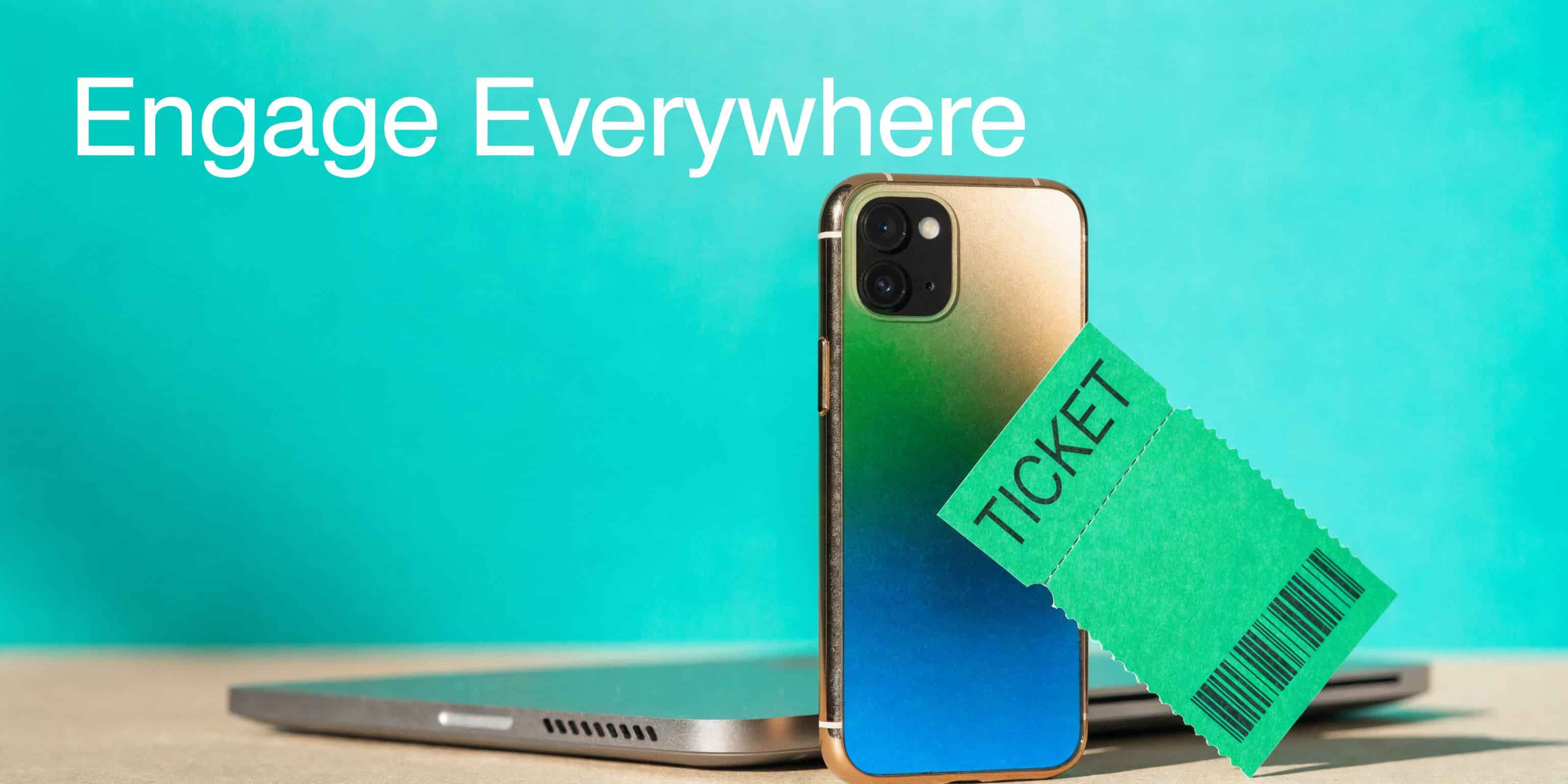 Smartphone with a gradient back rests on a laptop next to a green ticket icon.