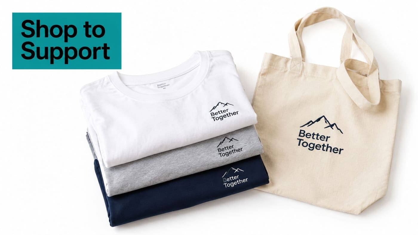 Folded branded t-shirts stacked beside a canvas tote for a nonprofit shop