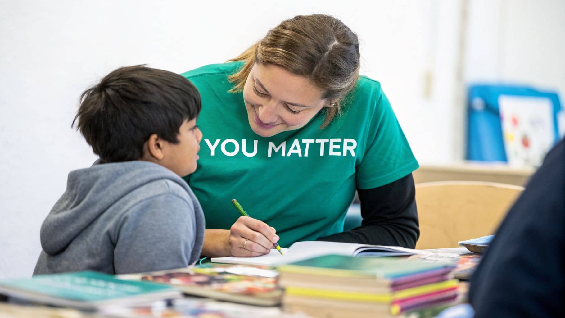 Volunteer tutor wearing a YOU MATTER shirt works with a smiling child